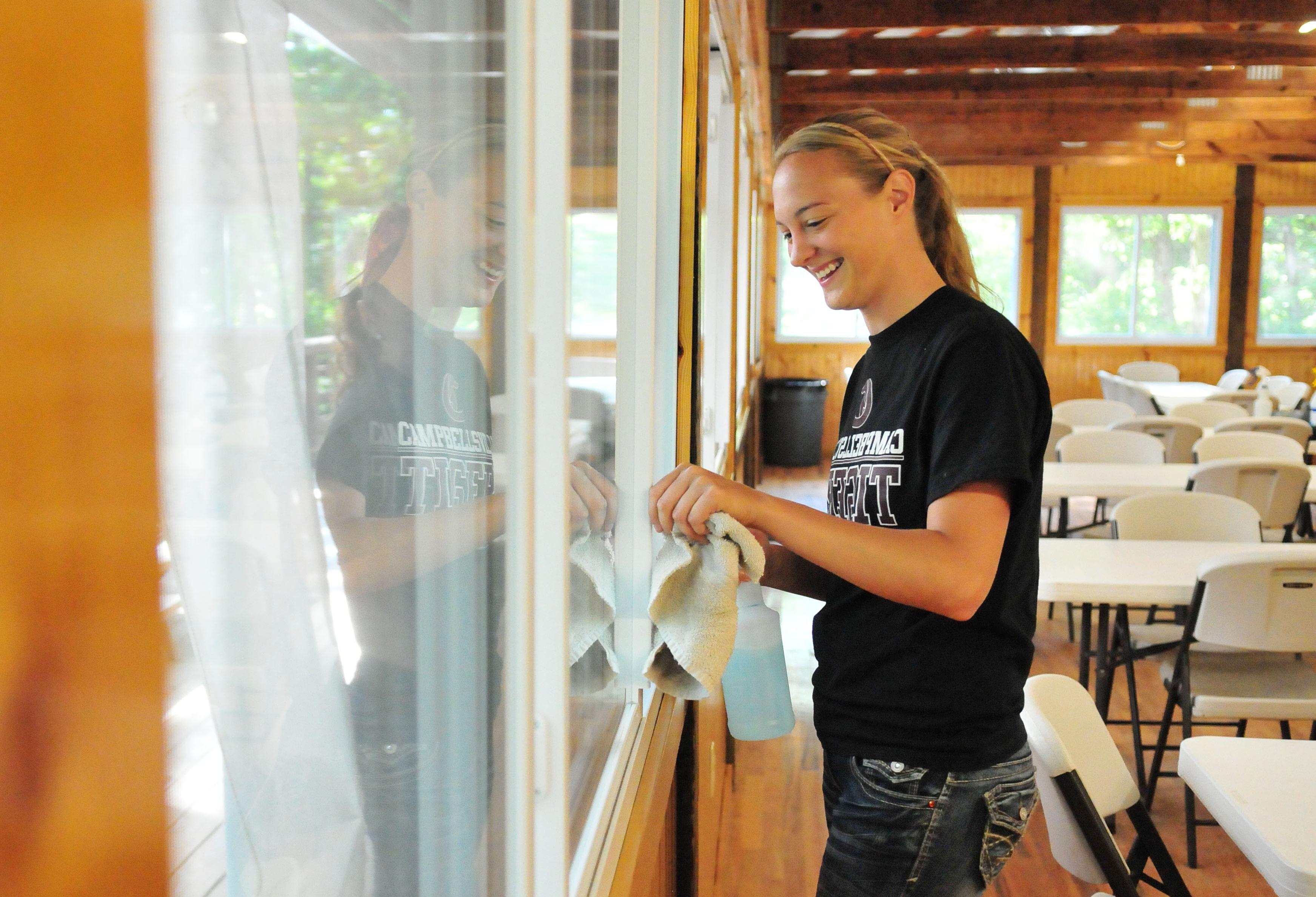 Kendyl Ahrens, a Campbellsville University junior from Poseyville, Ind., cleans windows at Camp Eagle.